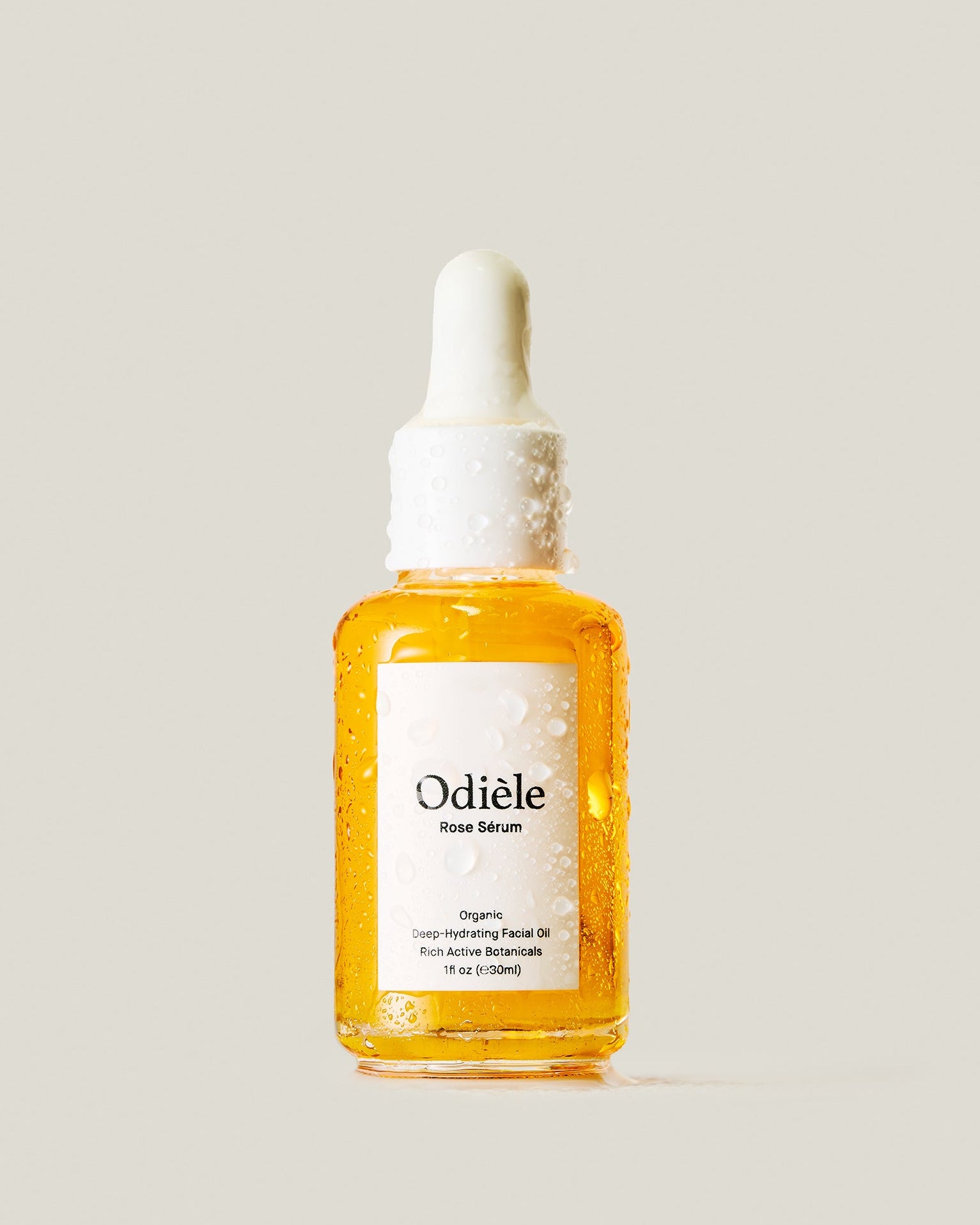 A bottle of Odiele Rose Serum with a white dropper cap, filled with a golden-yellow liquid, set against a solid light beige background.