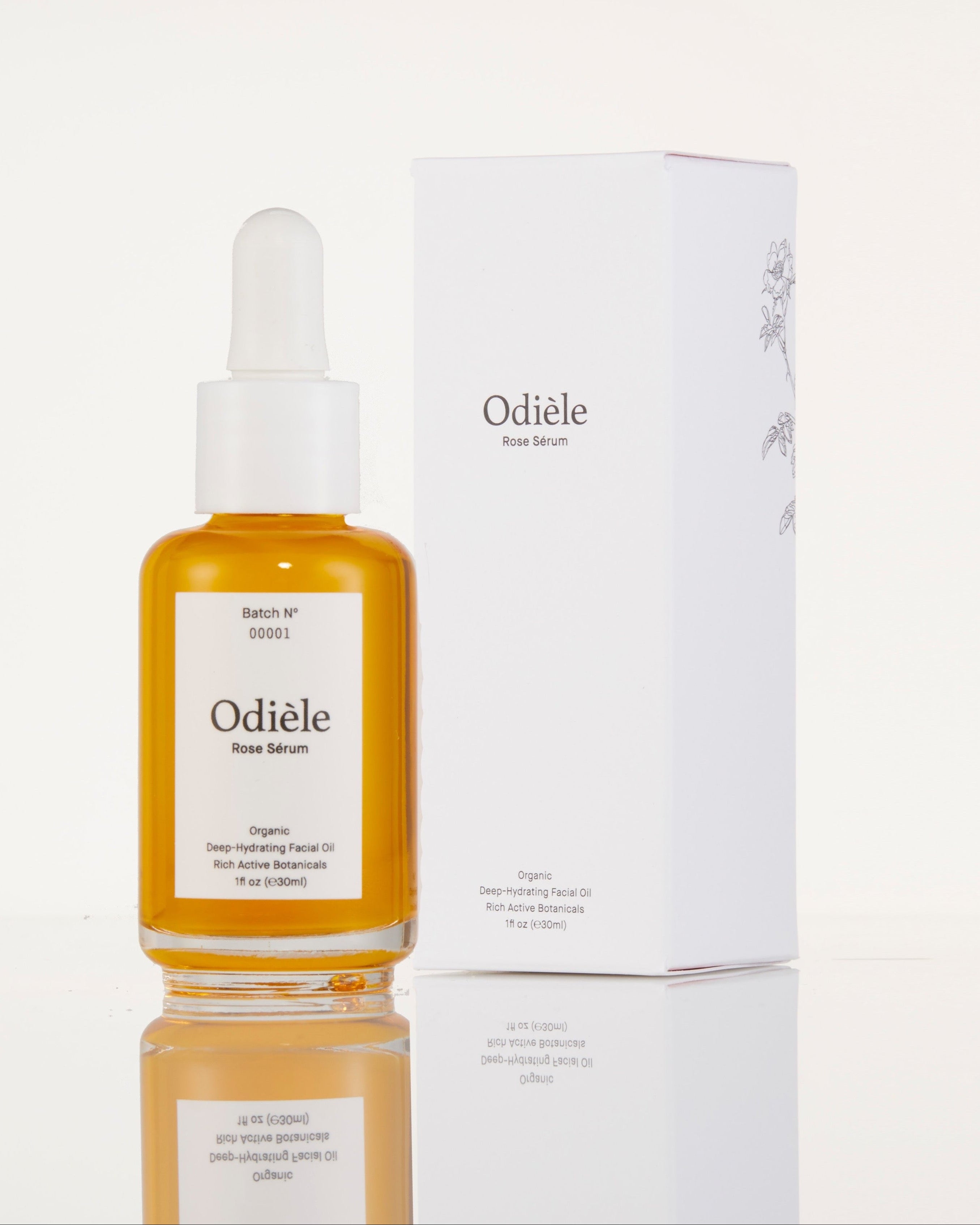 A bottle of Odiele Deep Moist serum with amber liquid and a white dropper cap stands next to its white packaging box on a reflective white surface.